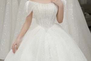 Một cô dâu xinh đẹp diện váy cưới trắng lấp lánh trong studio.
