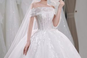 Cô dâu xinh đẹp diện váy cưới trắng lộng lẫy và khăn voan trong không gian studio.