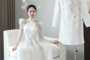Người mẫu mặc váy cưới trắng sang trọng cùng áo dài cưới nam trong không gian studio.