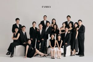 Bức ảnh chụp gia đình đông đủ các thế hệ với phong cách Hàn Quốc sang trọng trong trang phục đen trắng tại studio.