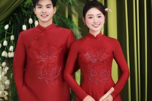 Cặp đôi mặc áo dài đỏ truyền thống tạo dáng trong studio với phông nền xanh sang trọng.