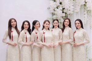 Nhóm các cô gái mặc áo dài trắng ngà chụp ảnh tại studio với hoa decor sang trọng.